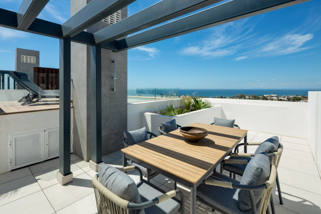 Spis utendørs på den romslige takterrassen, med panoramautsikt over havet og Costa del Sol.